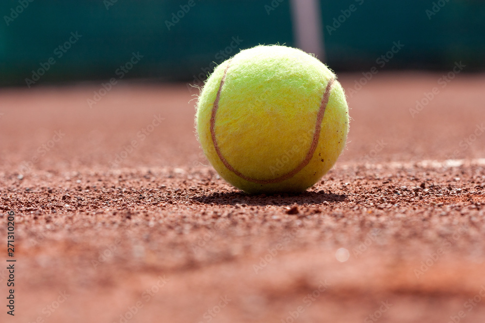 Close up of tennis ball on clay court.