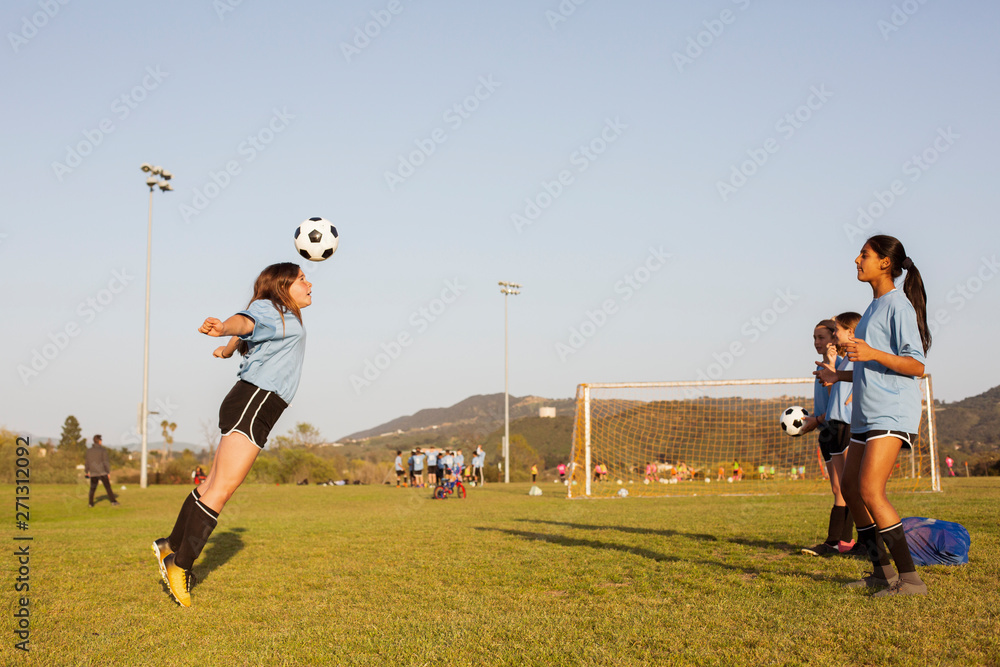 Fototapeta premium Girls practicing soccer in grassy field