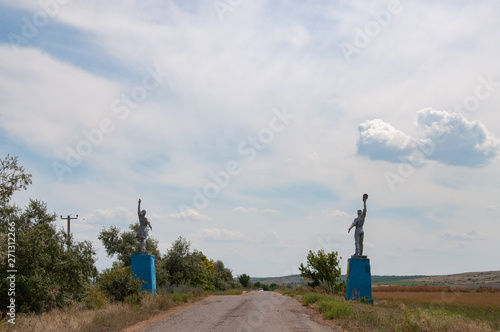 Silhouettes of Worker and Kolkhoz Woman style statues by roadsides. Social realism monuments in countryside of Ukraine. Monumental sculptures of Social-Realism. Non-urban landscape photo