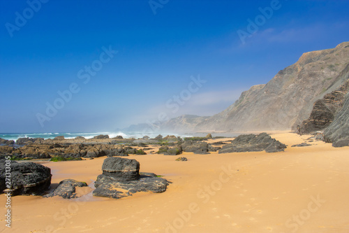 Rock formations and cliffs on beach, high waves on water of Atlantic Ocean. West coast of Algarve Portugal