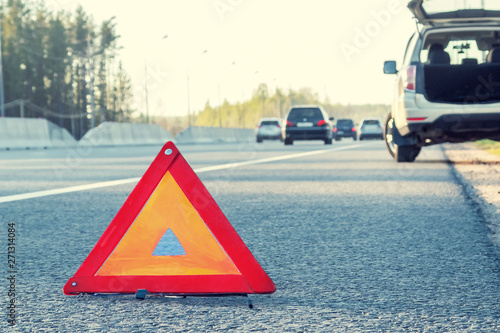 Broken car on the side of the highway and an emergency stop sign