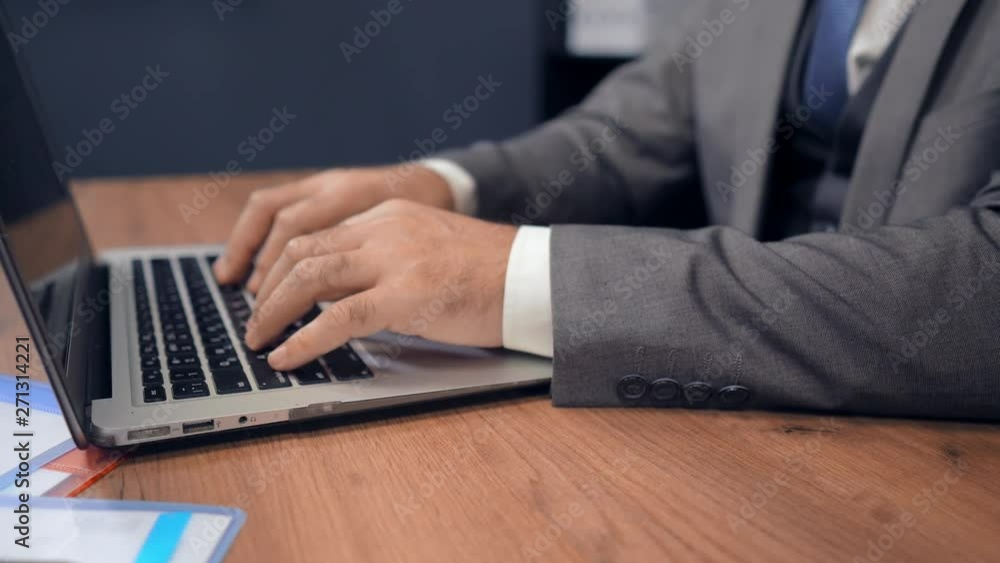 Businessman In Grey Suit Working On Laptop. Typing Report. Selective Focus On Hands And Laptop. Business Concept. Businessman In Grey Suit Working On Laptop. Typing Report. Selective Focus On Hands And Laptop. Business Concept.