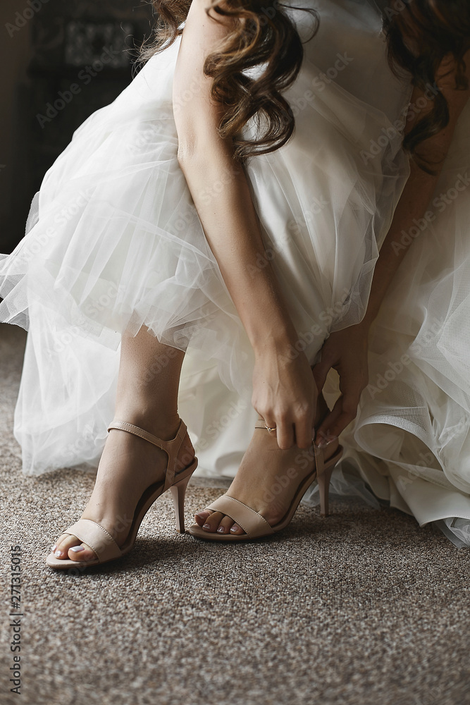 Beautiful female legs in stylish shoes on a high heel, the bride puts on wedding shoes on high heel
