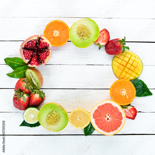 Fruits on a white wooden background. Mango, melon, pomegranate, strawberry, banana. Top view. Free space for your text.