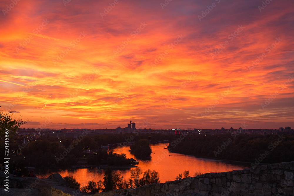 Dramatic, colorful city sunset. Orange, pink, and purple sky colors. Beautiful city skyline. The sky is on fire. Sunset over river. Danube and Sava rivers confluence in Belgrade, Serbia.