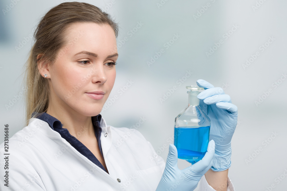 Fototapeta premium young female chemist with a liquid sample in front of laboratory