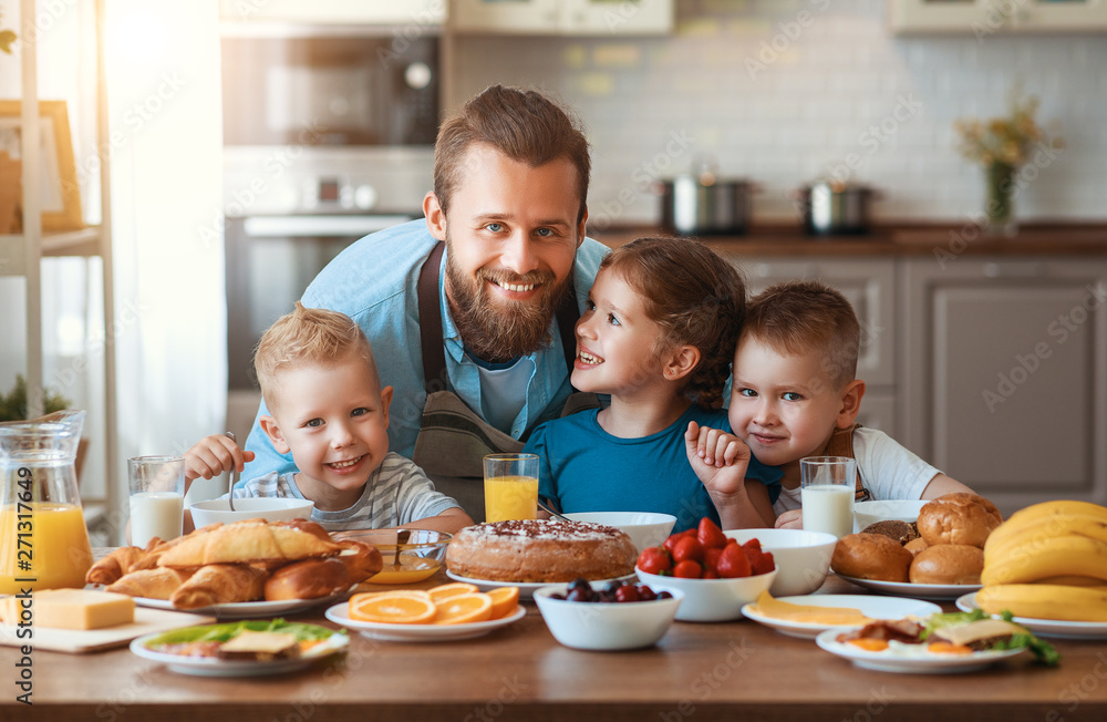 happy family father with children feeds his sons and daughter in kitchen with Breakfast. happy family father with children feeds his sons and daughter in kitchen with Breakfast.