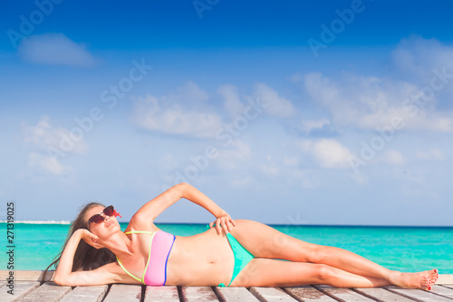 pretty longhaired womanin colorful bikini by the beach. Maldives