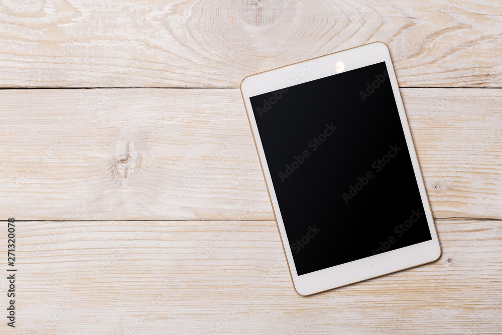 White digital tablet on wooden table. Top view with copy space. White digital tablet on wooden table. Top view with copy space.