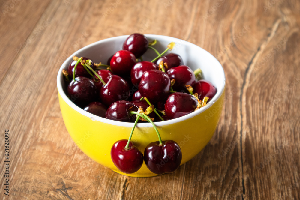 Fresh organic sweet cherries in a glass bowl on wooden table Fresh organic sweet cherries in a glass bowl on wooden table