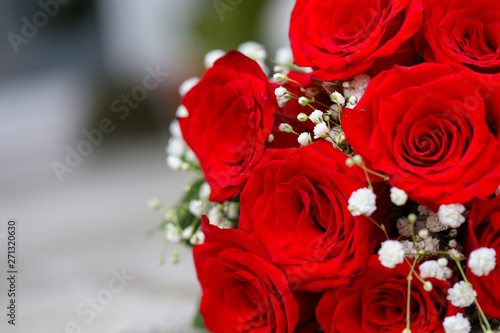 A bouquet of red roses with tiny white flowers and green leaves