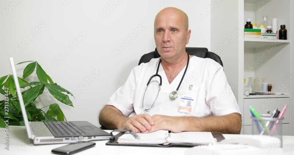Image with a Doctor in Hospital Cabinet Staying Serious and Listening a Patient Image with a Doctor in Hospital Cabinet Staying Serious and Listening a Patient