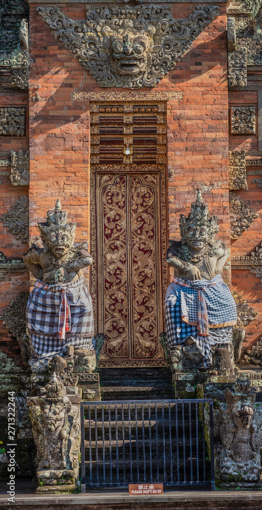 Ubud, Bali, Indonesia - February 26, 2019: Batuan Temple. Closeup of gray stone dwarapalakas, guards, in front of door of Kori Agung, main shrine.