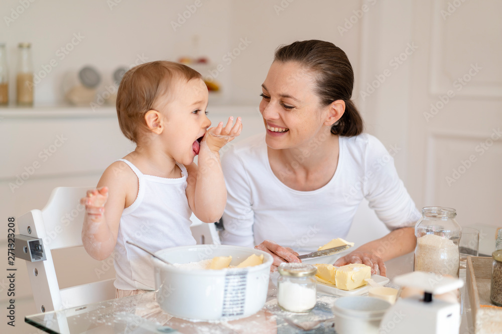 Happy mother and little daughter making a cake together in kitchen at home Happy mother and little daughter making a cake together in kitchen at home