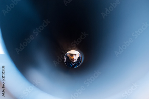 man looking through a pipe