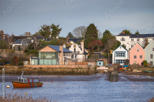Houses on the banks of the river Exe in Topham. An old fishing boat in the foreground is moored. Devon. UK