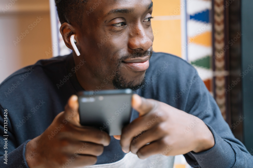 Smiling young man with wireless earphones and cell phone Smiling young man with wireless earphones and cell phone