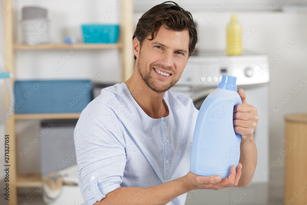 smiling young man holding laundry detergent smiling young man holding laundry detergent