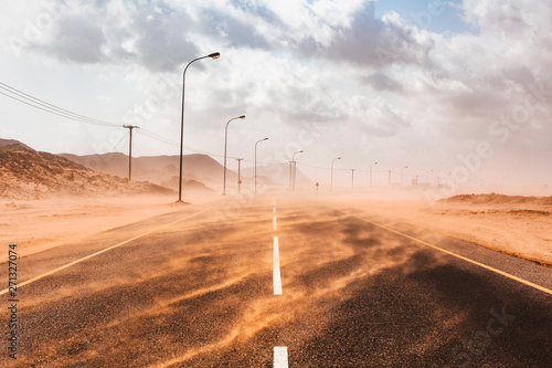 View of empty road passing through desert during sand storm
