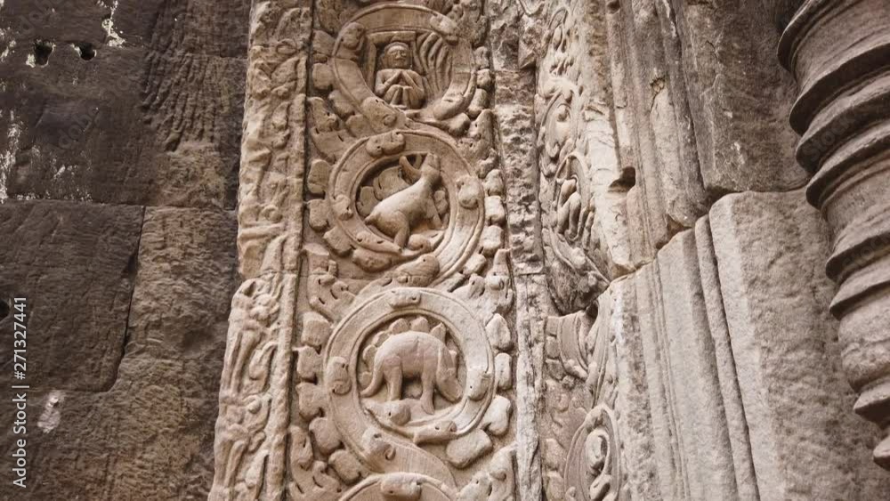 ancient bas-reliefs depicting a dinosaur in the ancient temple of TA Prohm. One of the most famous temples of Angkor, TA Prohm is known for its huge trees and roots growing from ancient bas-reliefs depicting a dinosaur in the ancient temple of TA Prohm. One of the most famous temples of Angkor, TA Prohm is known for its huge trees and roots growing from