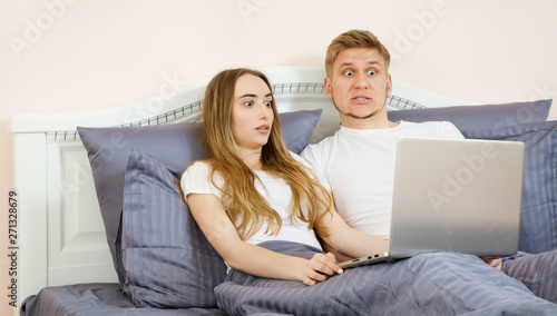 Closeup Surprised emotional white Lover or couple when using technology laptop on the bed in bed room at modern home, couple watching something emotional on laptop in the bed