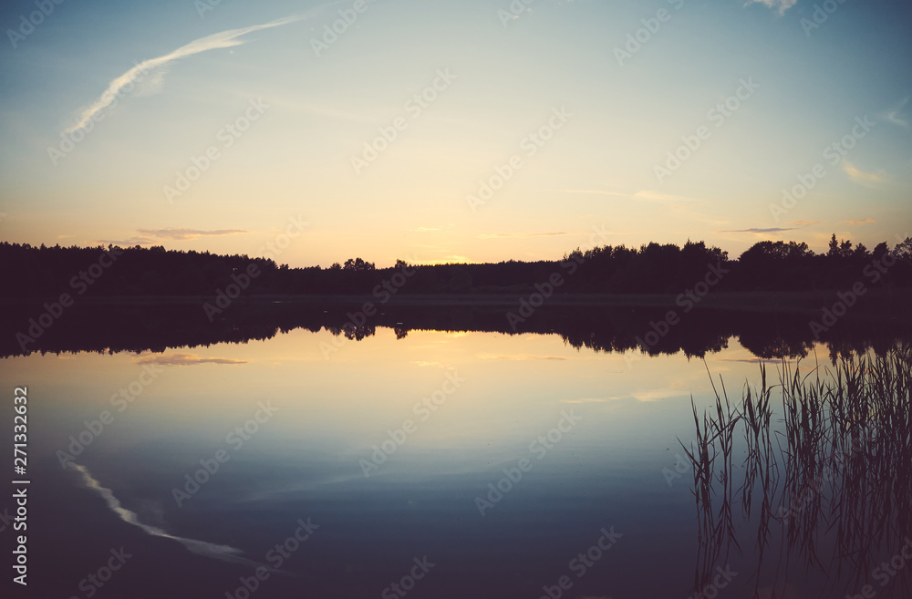Scenic sunset reflected in a calm lake, color toning applied.