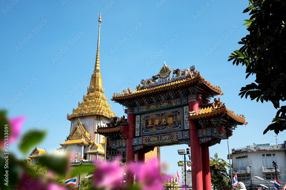 Naklejka premium Architectural detail of Buddhist temple, Wat Traimit and Chinatown Gate over blue sky in Bangkok, Thailand