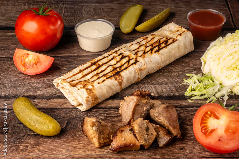 Takeaway fast food in pita bread with fresh vegetables, pork and sauce Takeaway fast food in pita bread with fresh vegetables, pork and sauce