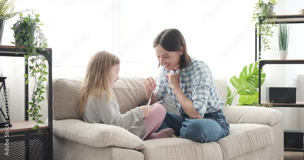 Joyful mother with her daughter sitting on sofa and drawing on notepad at home Joyful mother with her daughter sitting on sofa and drawing on notepad at home
