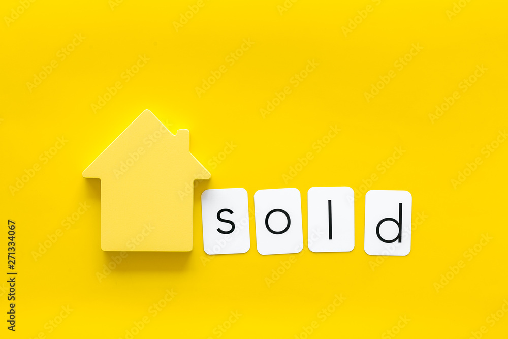 Mortgage credit concept with house toy and sold copy on yellow background top view Mortgage credit concept with house toy and sold copy on yellow background top view
