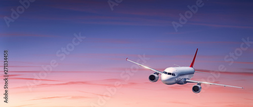 Passenger airplane is flying in colorful sky at sunset. Landscape with white airplane, purple sky with pink clouds at dusk. Aircraft is landing. Business trip. Commercial plane. Travel. Aerial view