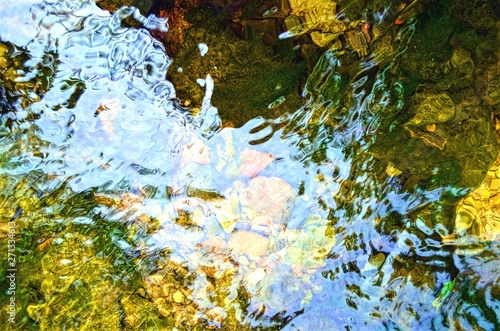 eflections and ripples on the surface of the current of the river, with visible rocks under the water photo