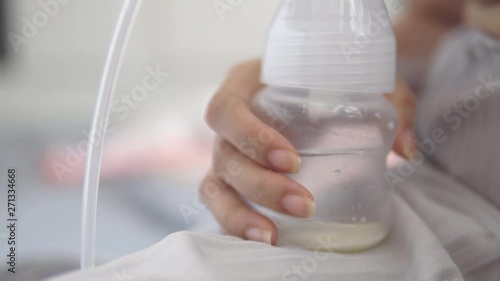 Young mother using electric breast pump pumping breast milk feeding for her baby.