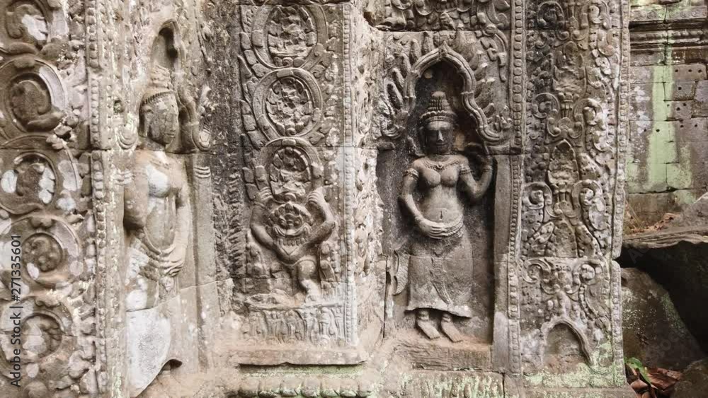 ancient bas-reliefs depicting the divine dancer Apsara in the temple of TA Prohm. One of the most famous temples of Angkor, TA Prohm is known for its huge trees and roots growing from its walls. ancient bas-reliefs depicting the divine dancer Apsara in the temple of TA Prohm. One of the most famous temples of Angkor, TA Prohm is known for its huge trees and roots growing from its walls.