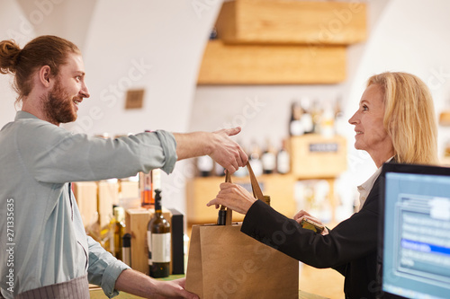 Fotografía Side view portrait of contemporary man selling wine to woman in shop