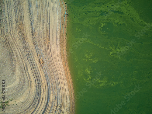 Aerial view of the Valdecañas reservoir, with green water from the algae and natural lines of the descent of the water. Natural texture photo