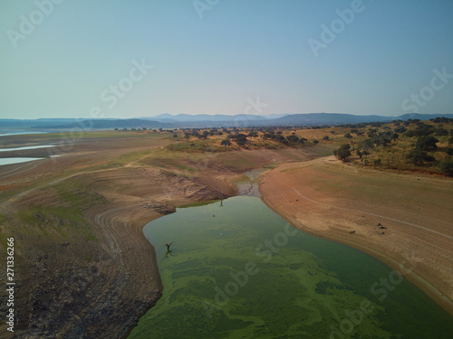 Aerial view of the Valdecañas reservoir, with green water from the algae and natural lines of the descent of the water. Natural texture