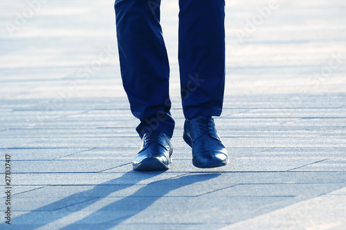 legs of a man walking on a city street.