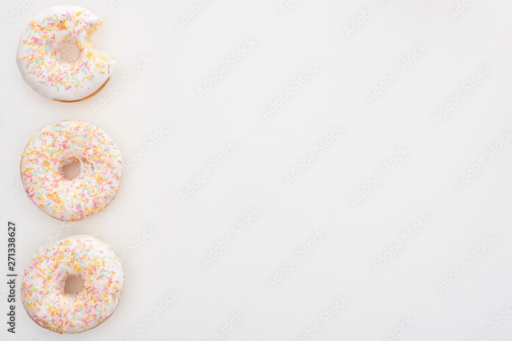 top view of tasty whole doughnuts with sprinkles near bitten one on white background top view of tasty whole doughnuts with sprinkles near bitten one on white background