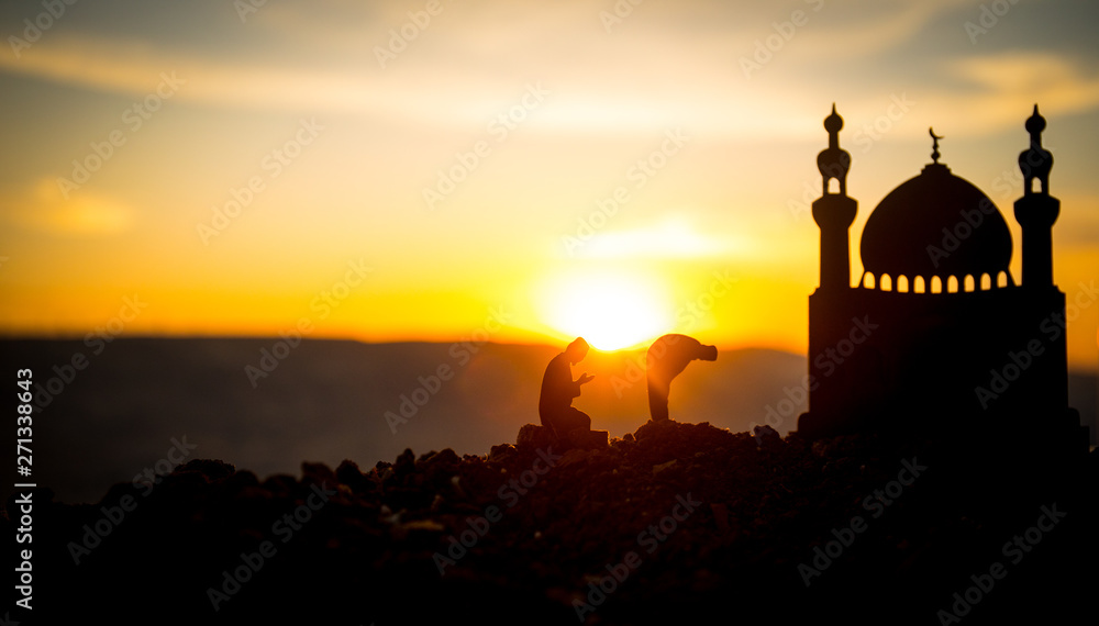 Concept of religion Islam. Silhouette of man praying on the background of a mosque at sunset