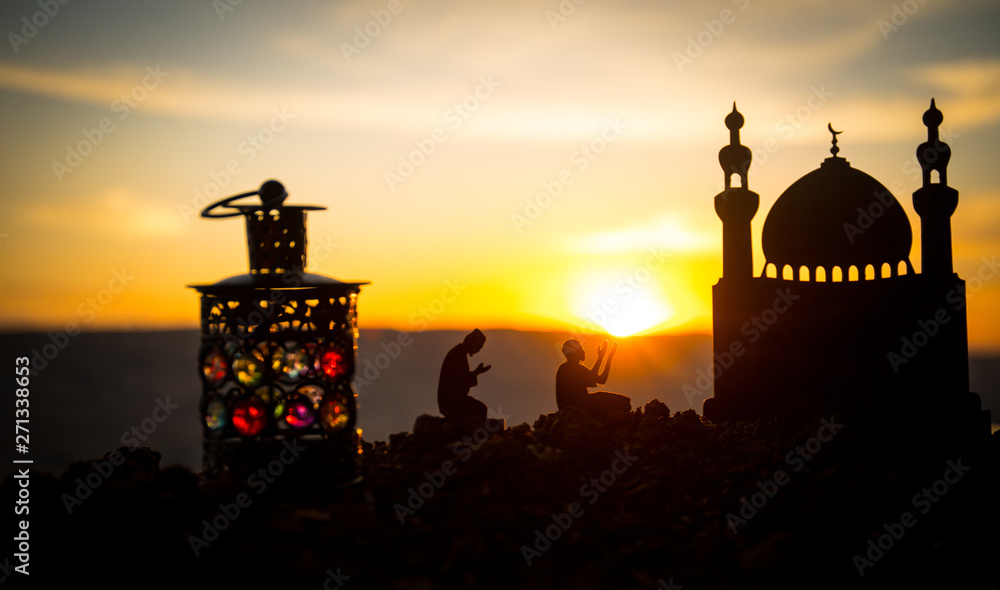 Concept of religion Islam. Silhouette of man praying on the background of a mosque at sunset