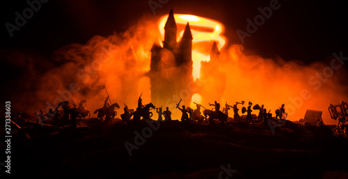 Medieval battle scene with cavalry and infantry. Silhouettes of figures as separate objects, fight between warriors on dark toned foggy background with medieval castle.