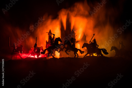 Medieval battle scene with cavalry and infantry. Silhouettes of figures as separate objects, fight between warriors on dark toned foggy background with medieval castle.