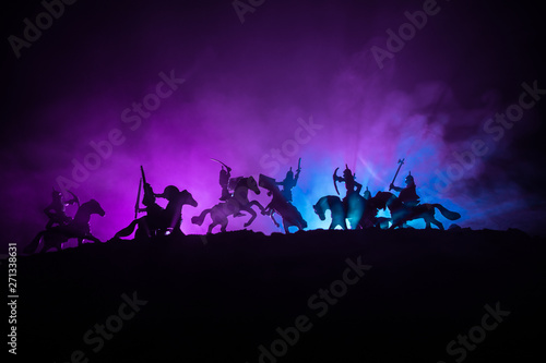 Medieval battle scene with cavalry and infantry. Silhouettes of figures as separate objects, fight between warriors on dark toned foggy background with medieval castle.