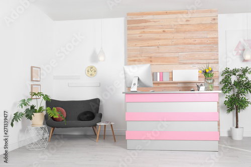Stylish interior of beauty salon with modern reception desk near wooden wall