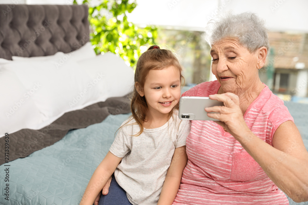 Cute girl and her grandmother taking selfie  at home