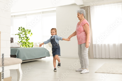 Cute girl and her grandmother dancing at home