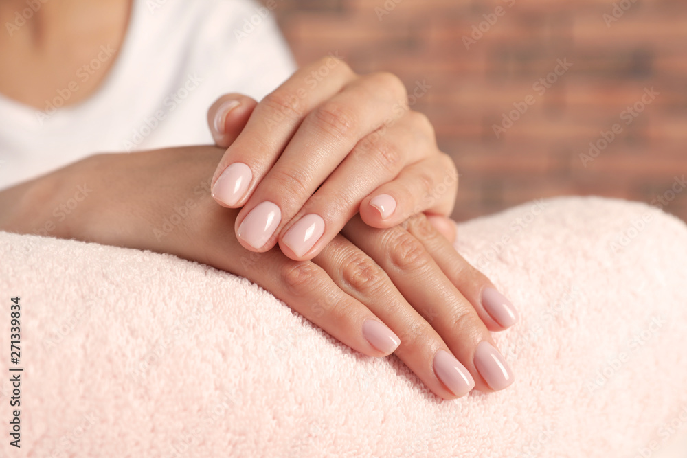 Woman showing neat manicure on towel, closeup. Spa treatment