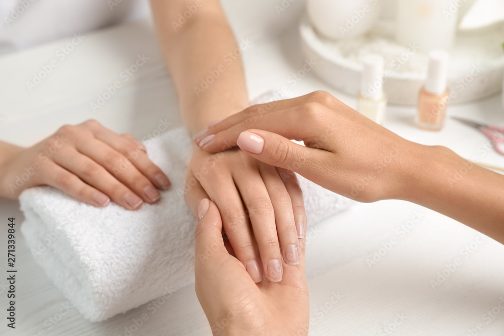 Cosmetologist massaging client's hand at table in spa salon, closeup Cosmetologist massaging client's hand at table in spa salon, closeup