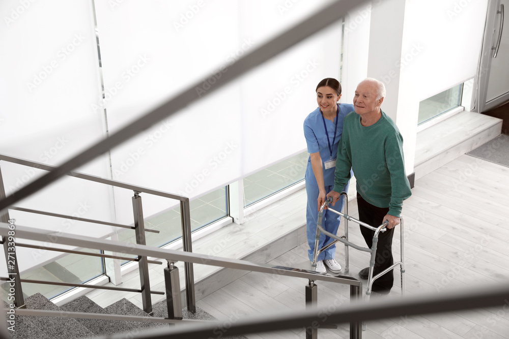 Fototapeta premium Nurse assisting senior man with walker in hospital